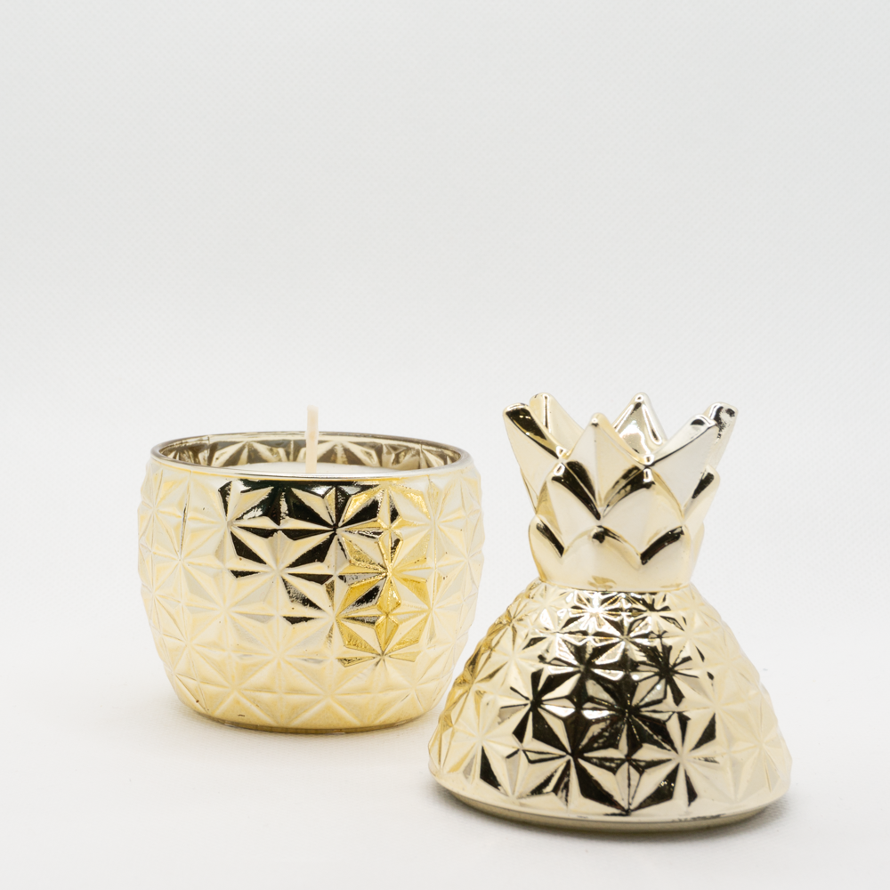 A picture of a golden pineapple shaped candle with the lid removed showing the candle within