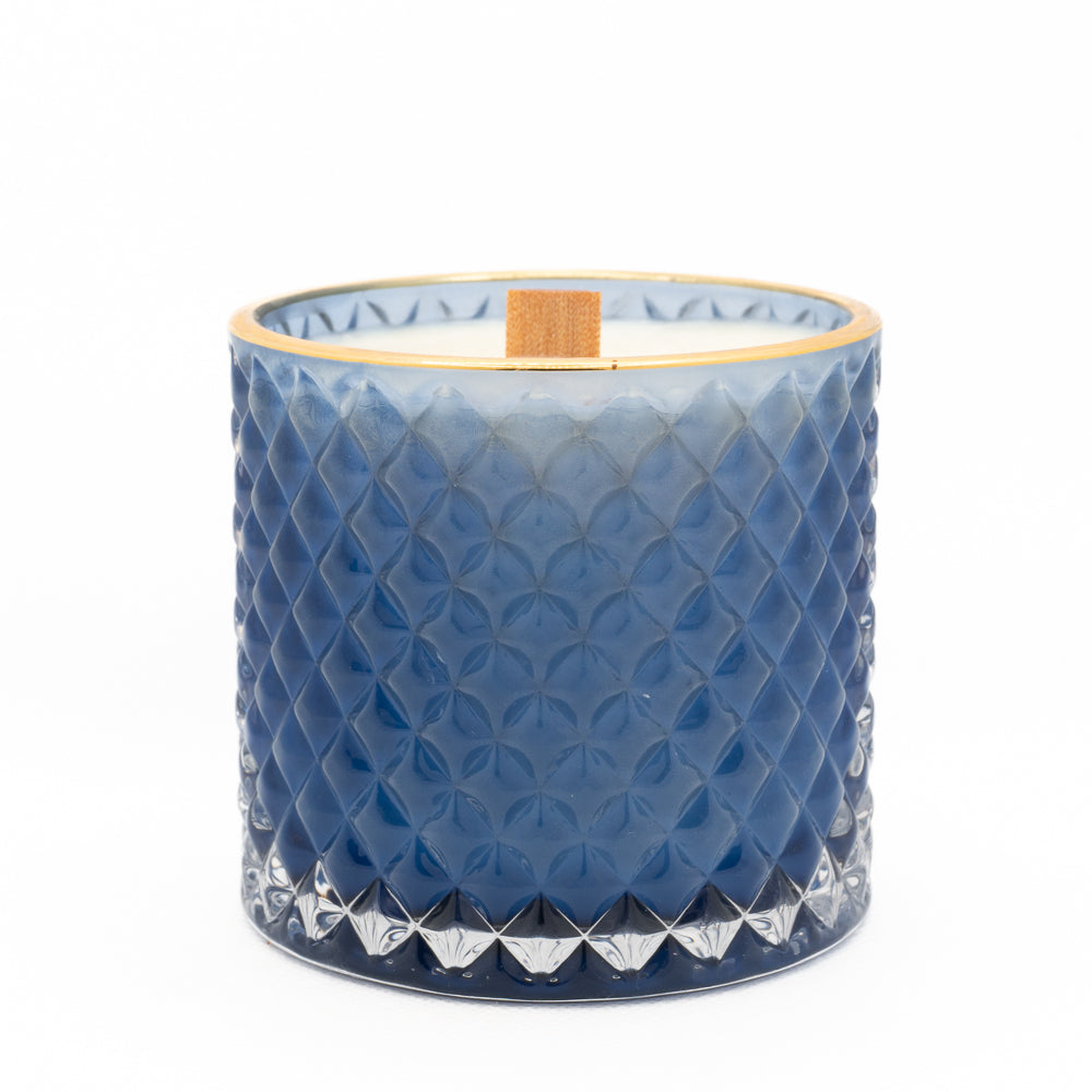 lid removed from candle, blue and gold with wooden wick showing. 